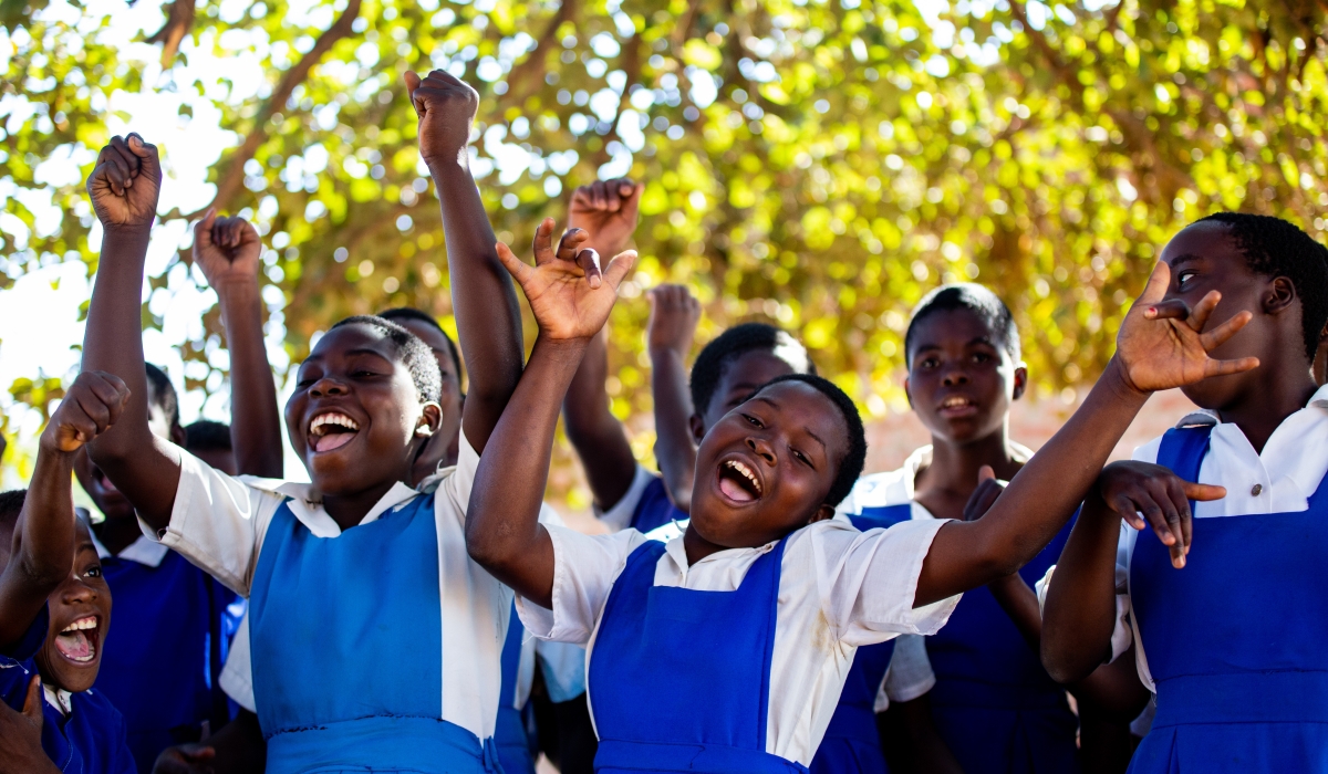 (Front left to right) Sharifa, 13, Florence, 14, and Grace, 14, cheer alongside their fellow classmates outside their school in Salima, Malawi to celebrate that trachoma has been eliminated in the coun