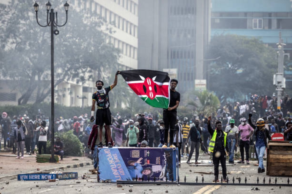 Protesters hold a Kenyan flag outside the Kenyan Parliament after storming the building during a nationwide strike to protest against tax hikes and the Finance Bill 2024 in downtown Nairobi, on June 25, 2024. (Photo by LUIS TATO/AFP via Getty Images)