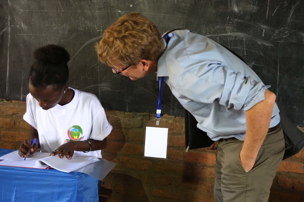 One of the European Union observers checks out what a National Electoral Commission volunteer is doing at the Kimironko II polling site, in Kigali, during the parliamentary elections on September 3, 2018. Photo by  Sam Ngendahimana