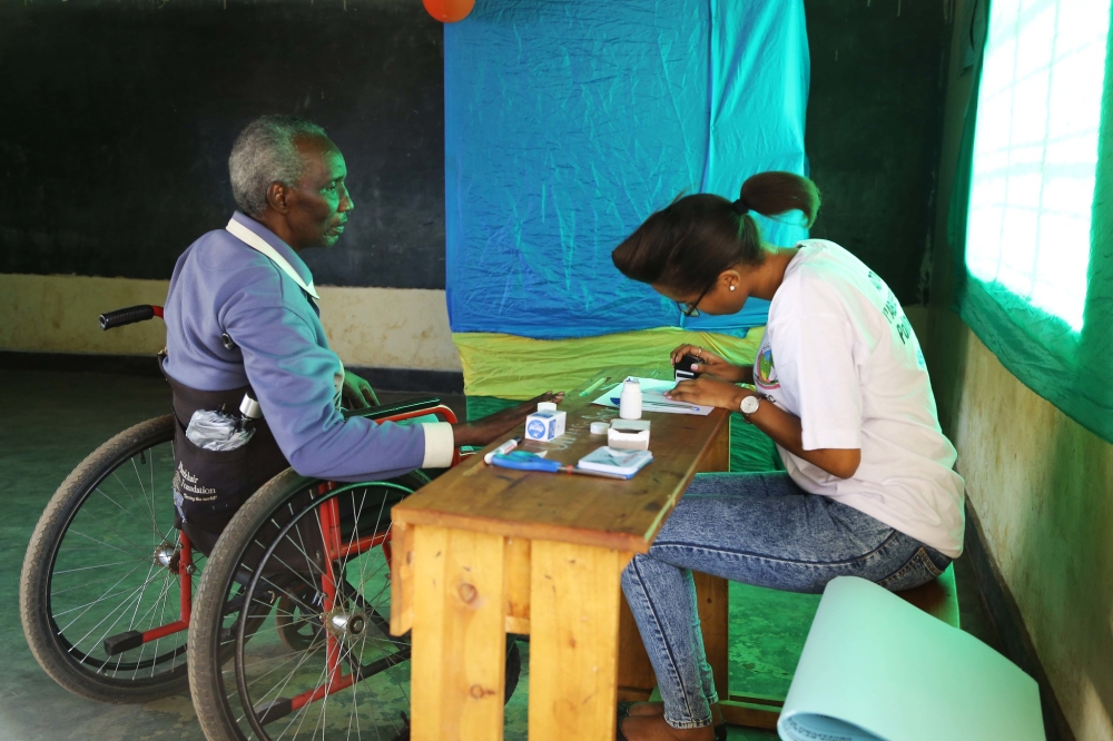 A voter with disabilities is served during the parliamentary elections in 2018. This years, according to NEC, there are 2,593 polling stations in total, including 2,433 within the country. Sam Ngendahimana