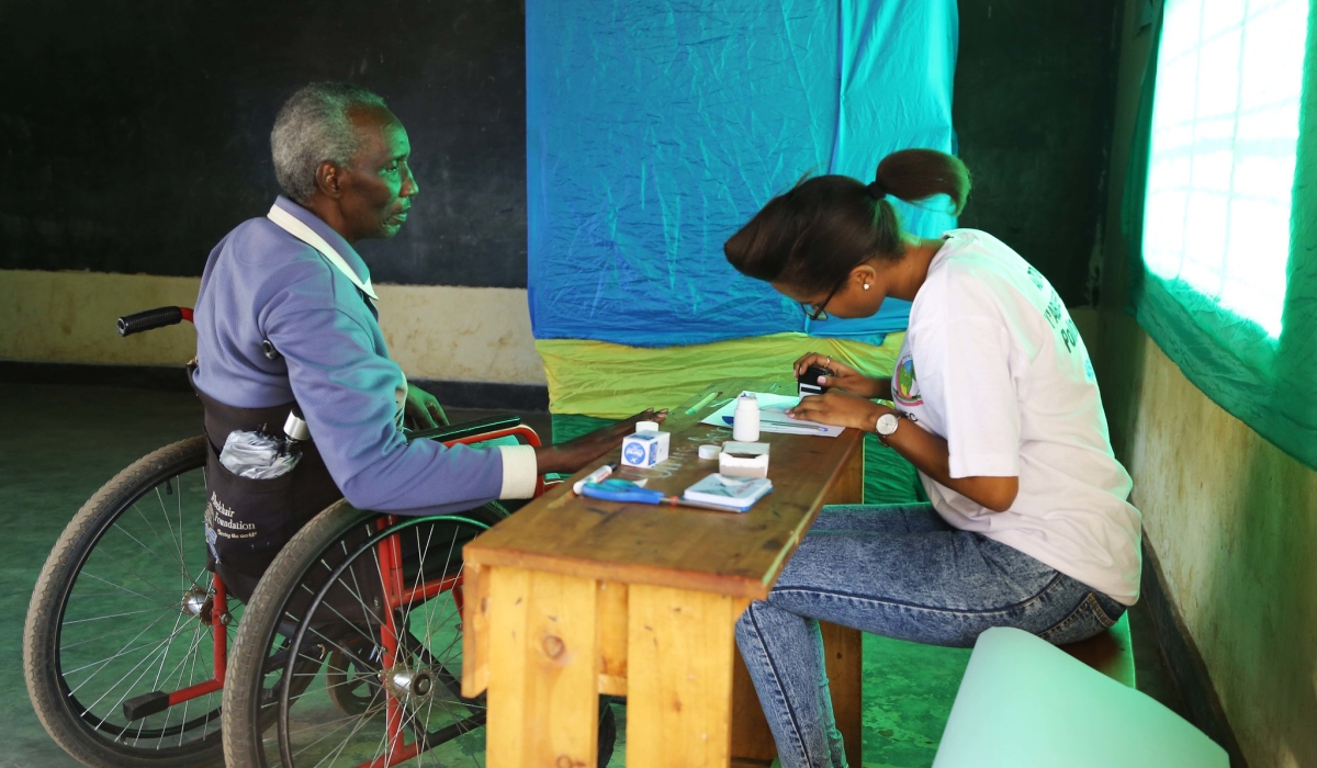 A voter with disabilities is served during the parliamentary elections in 2018. This years, according to NEC, there are 2,593 polling stations in total, including 2,433 within the country. Sam Ngendahimana