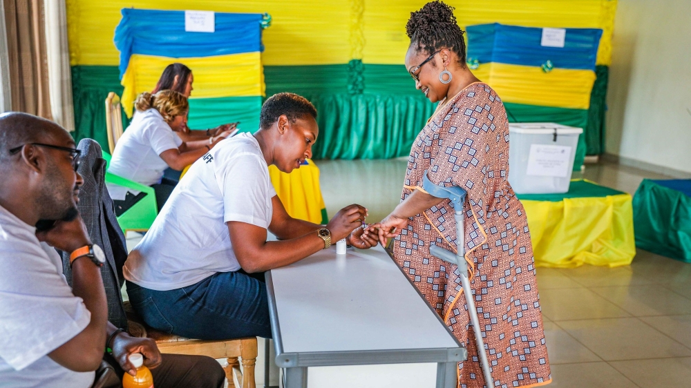 A volunteer help a resident with disability after casting her vote at the polling site in Nyarugenge District. Photos by Craish Bahizi