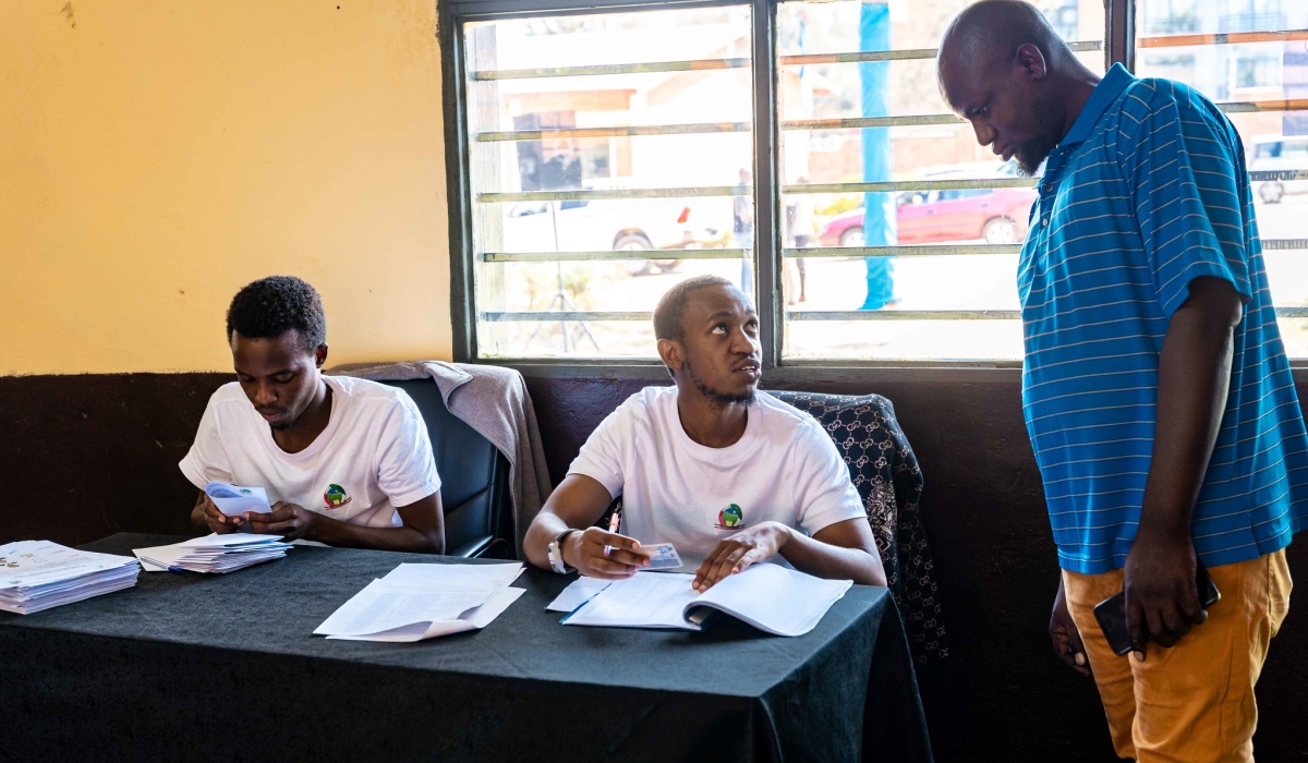 NEC volunteers help a voter before csting his vote during the presidential and parliamentary elections, on July 15. Photo by Craish Bahizi