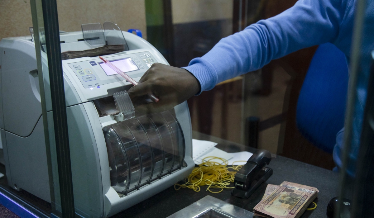 A bank teller counts money as he serves a customer at Bank of Kigali main branch (File)