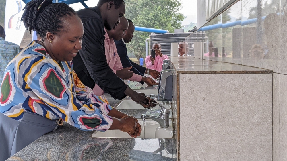 Officials wash hands at the new water sanitation and hygiene facility during the closing ceremony of the project in Rugerero Sector, Rubavu District, on Tuesday, July 30,