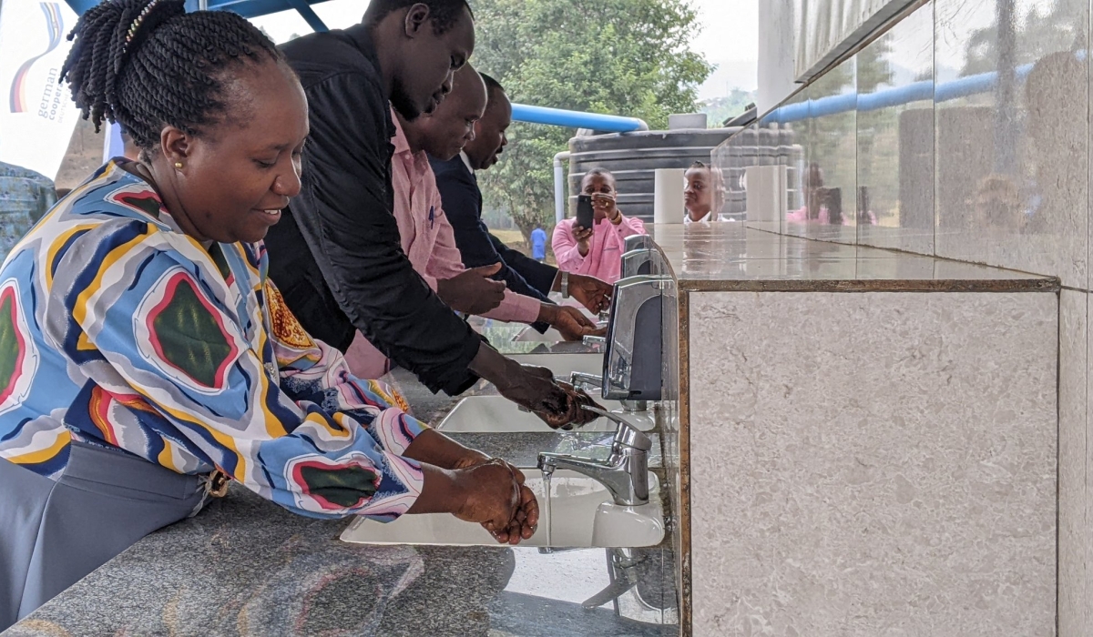 Officials wash hands at the new water sanitation and hygiene facility during the closing ceremony of the project in Rugerero Sector, Rubavu District, on Tuesday, July 30,