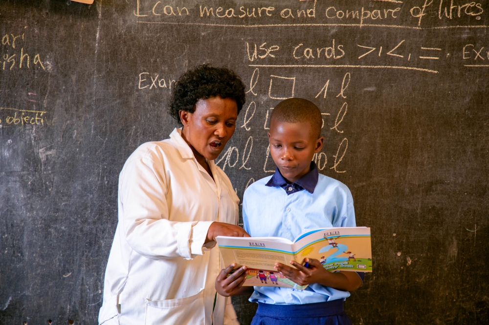 A teacher assists a student while reading a book during a class at GS Kimisange. Rwanda plans to spend Rwf792.7 billion on education in the current fiscal year – 2024-2025. PHOTO BY DAN GATSINZI