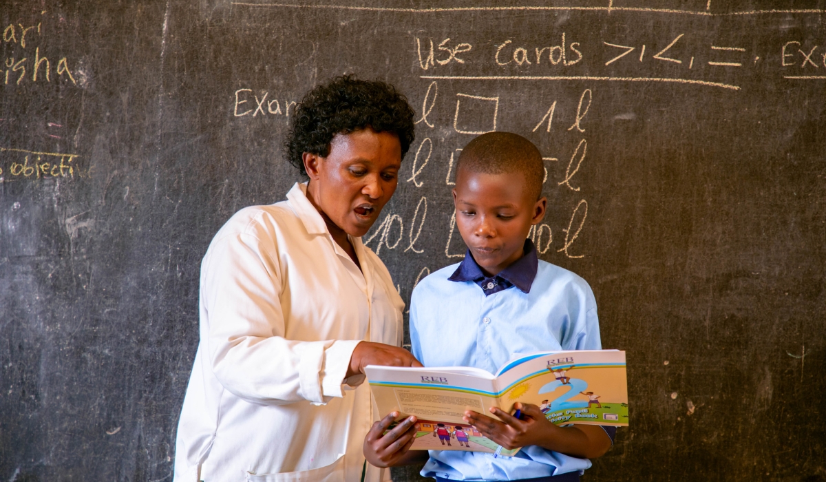 A teacher assists a student while reading a book during a class at GS Kimisange. Rwanda plans to spend Rwf792.7 billion on education in the current fiscal year – 2024-2025. PHOTO BY DAN GATSINZI