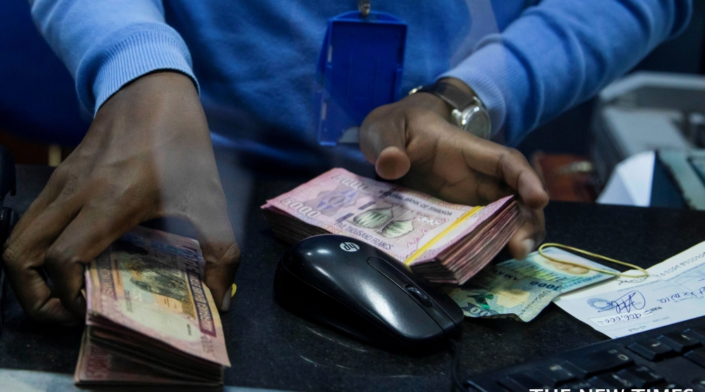 A bank teller counts money while serving customers at Bank of Kigali head office. File (2)