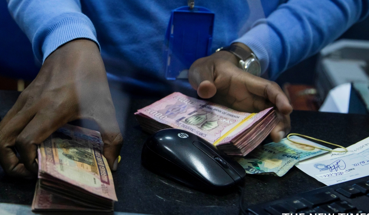 A bank teller counts money while serving customers at Bank of Kigali head office. File (2)