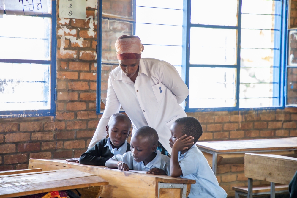 A  teacher inspects who students do their work during the remedial course programme for lower primary pupils  at GS Mayange B - Copy