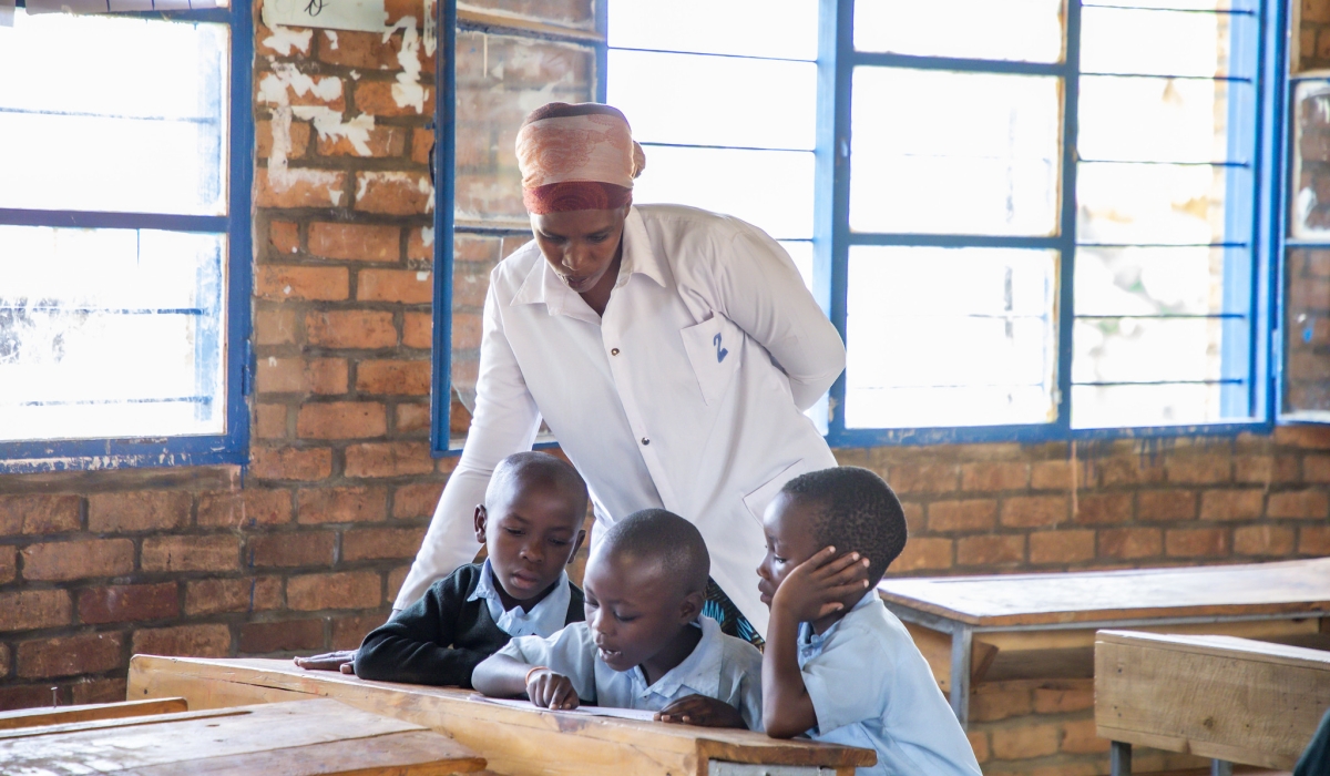 A  teacher inspects who students do their work during the remedial course programme for lower primary pupils  at GS Mayange B - Copy