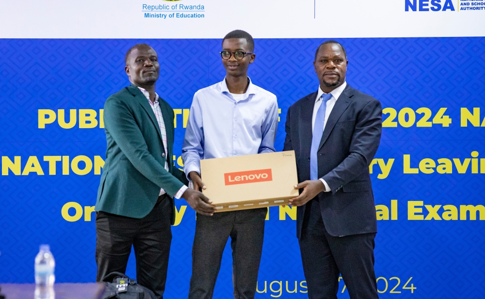 Denys Prince Tuyisenge and his father Denis Nzabonariba (left) receive a laptop as an award from Bernard Bahati, the Director General of National Examination and School Inspection Authority on Tuesday, August 27. Photo by Emmanuel Dushimimana