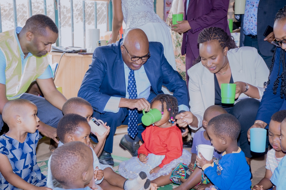 Carrying forward the legacy of parenting and care, Prof. Gicharu and Elodie Shamie help children drink milk during the ceremony