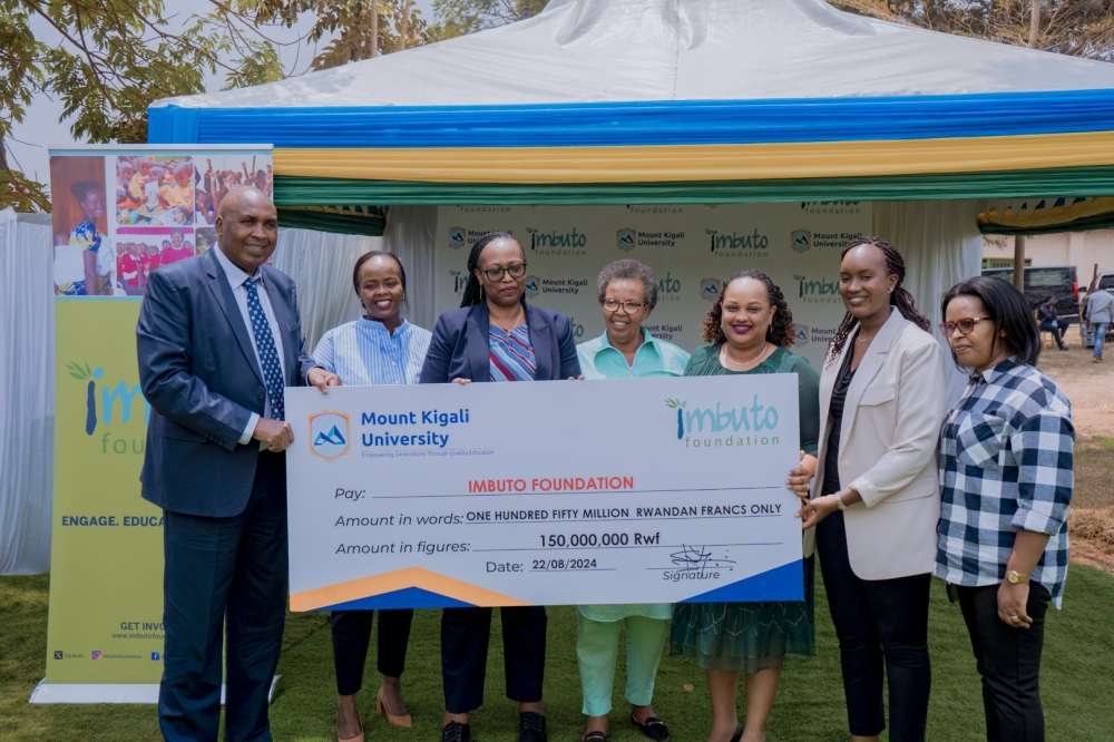 Prof. Simon Gicharu and Elodie Shamie display a dummy cheque worth Rwf150,000,000 as members from Imbuto Foundation, Kicukiro district, and the National Child Development Agency look on. The money will go towards the construction of the centre.