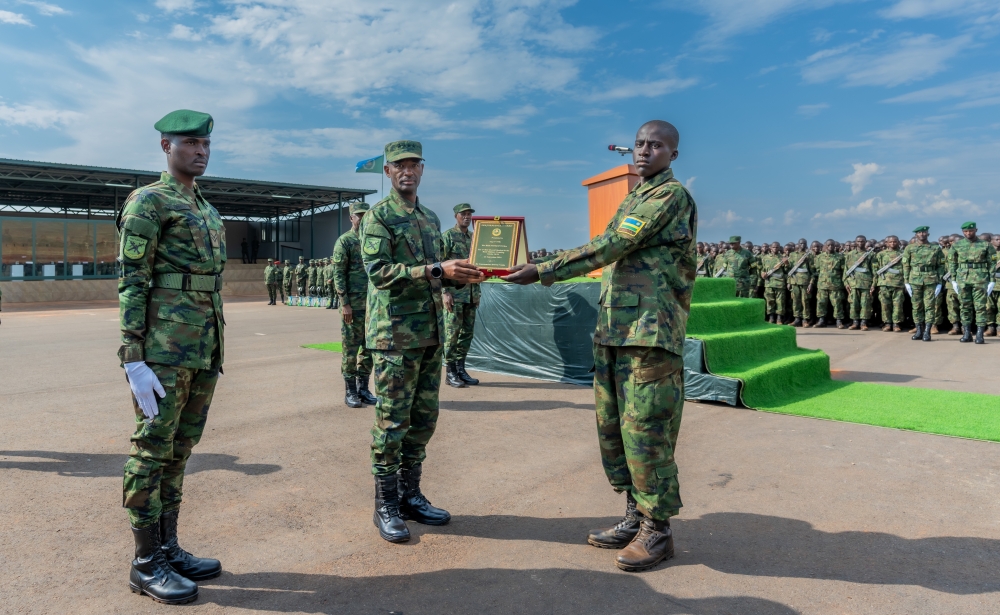 Gen Mubarakh Muganga hands over an award to one of the best performers during the pass-out event at the basic military training centre in Nasho in Kirehe District.