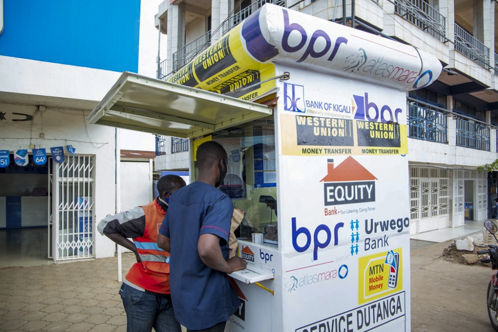 Two men carry out a transaction at a bank agent stall in Kimironko, a Kigali suburb. According to the Central Bank, the financial sector assets grew by 20.8 per cent in the first half of 2024. Photo: Craish Bahizi.