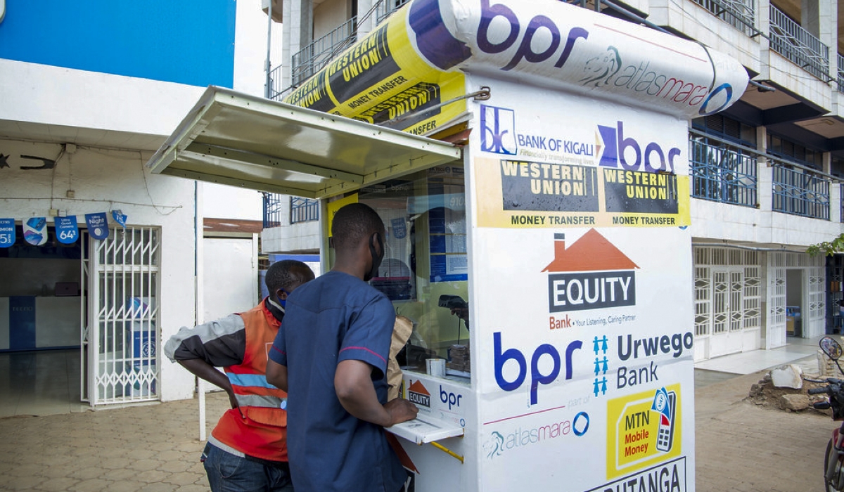 Two men carry out a transaction at a bank agent stall in Kimironko, a Kigali suburb. According to the Central Bank, the financial sector assets grew by 20.8 per cent in the first half of 2024. Photo: Craish Bahizi.