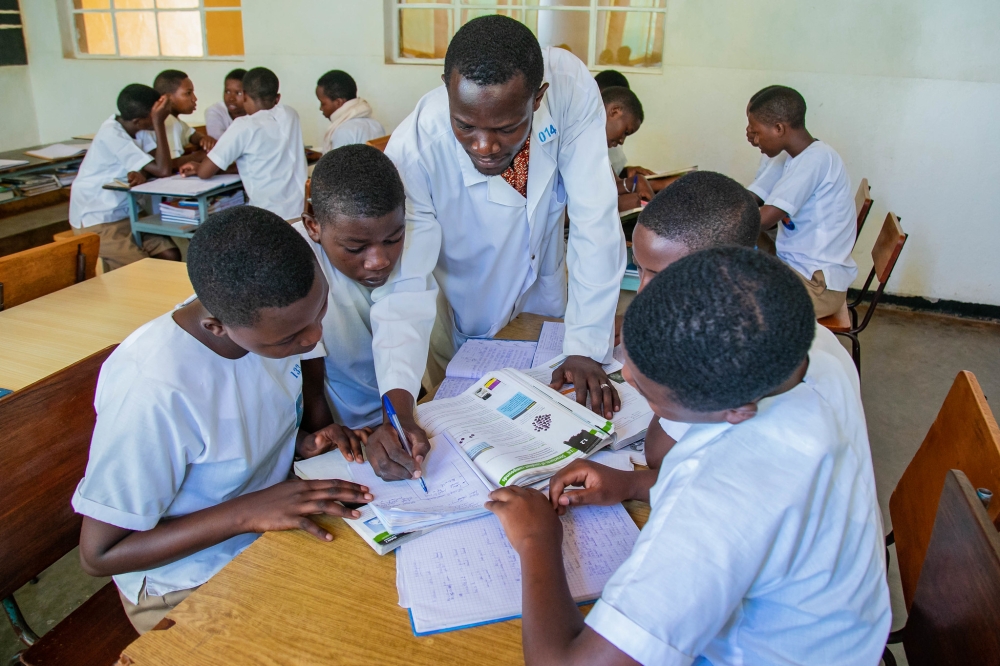 A teacher helps students during group work at Institut Sainte Famille de Nyamasheke. Photo: Courtesy