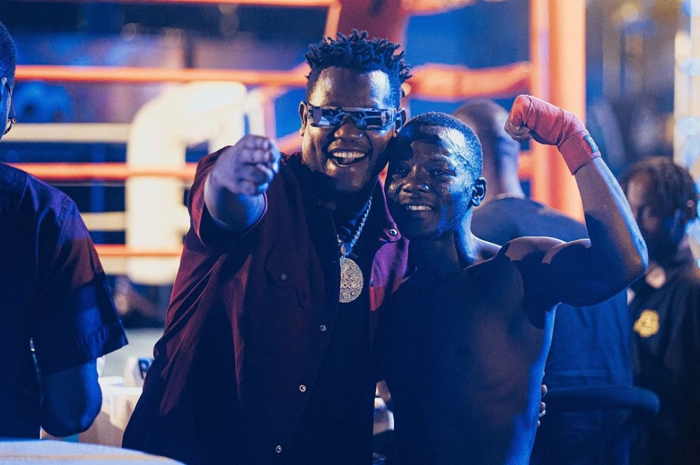 Singer Bruce Melodie shares a moment with a boxer at a previous Universe Boxing Championship event. The third edition returns this Sunday. COURTESY