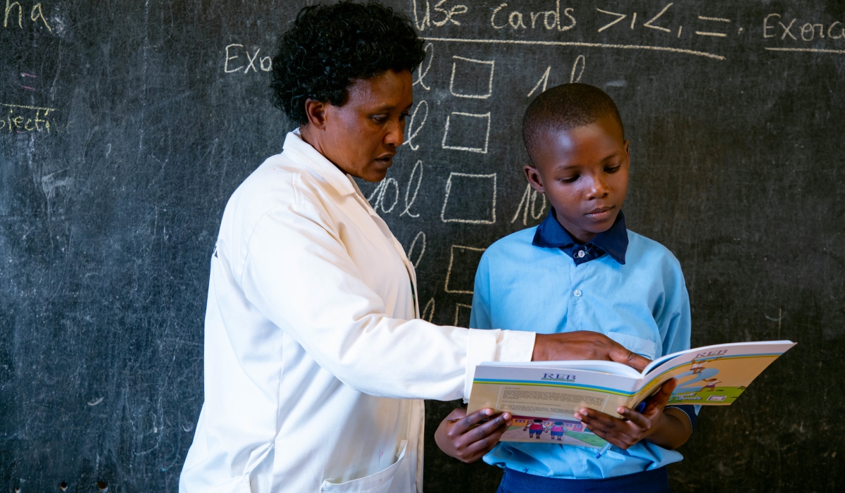 A teacher helps a student during a reading course at GS Kimisange in Kigali. Photo by Dan Gatsinzi