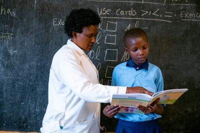 A teacher helps a student during a reading course at GS Kimisange in Kigali. Photo by Dan Gatsinzi