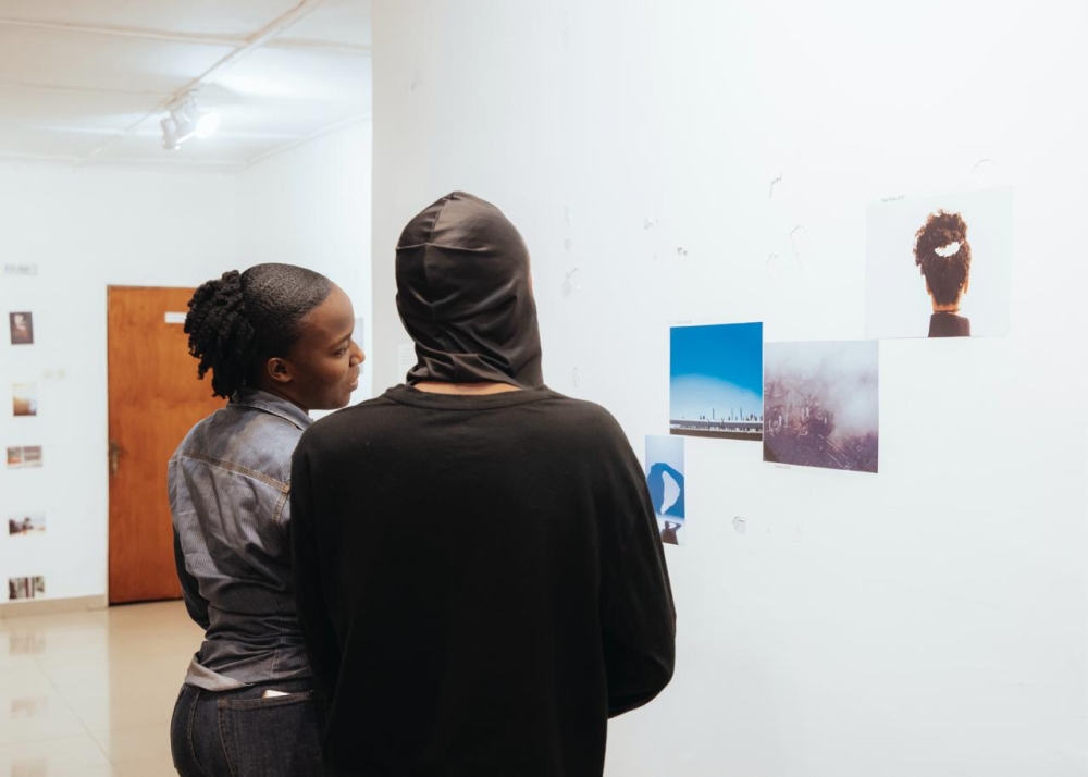 Rwandan photographer Alain Jules Hirwa (R) gives details to a visitor of his  solo exhibition of 40 photographs at L’Espace, Kimihurura. Courtesy