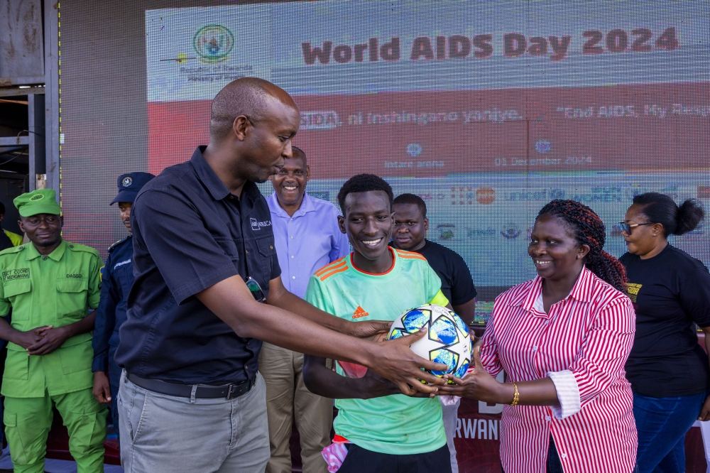 Dr. Lambert Rangira, the Country Programs Manager for AHF Rwanda hands over a ball to the Muyira team fter winning a  competition during an event to mark the World AIDS Day event. Courtesy