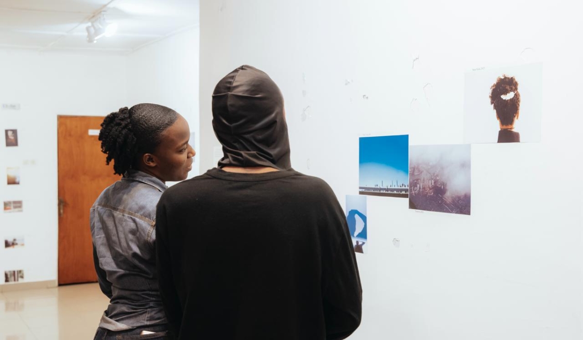 Rwandan photographer Alain Jules Hirwa (R) gives details to a visitor of his  solo exhibition of 40 photographs at L’Espace, Kimihurura. Courtesy