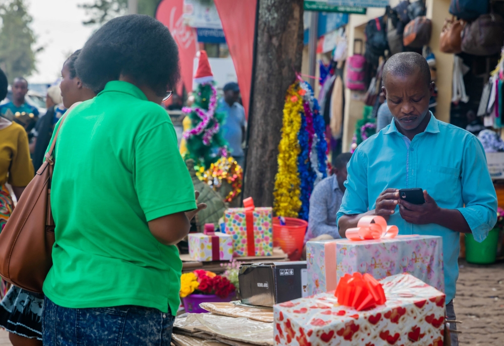 A shopper excitedly selects and pays for a gift ahead of the festive season at a lively Kigali store. Photo by Craish Bahizi