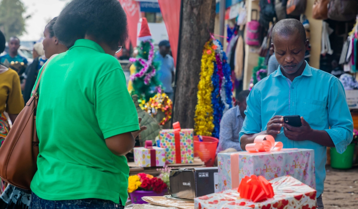 A shopper excitedly selects and pays for a gift ahead of the festive season at a lively Kigali store. Photo by Craish Bahizi