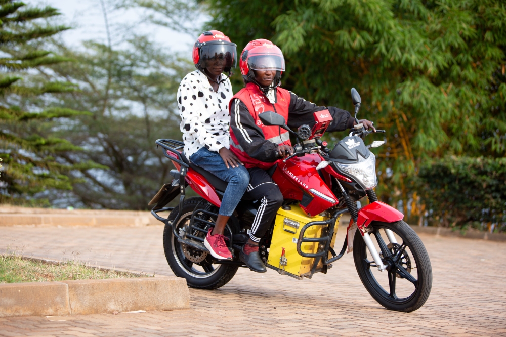 A female taxi moto driver Josie Nsanzingoma and her client on an  Ampersand e-motorbike in Kigali. File