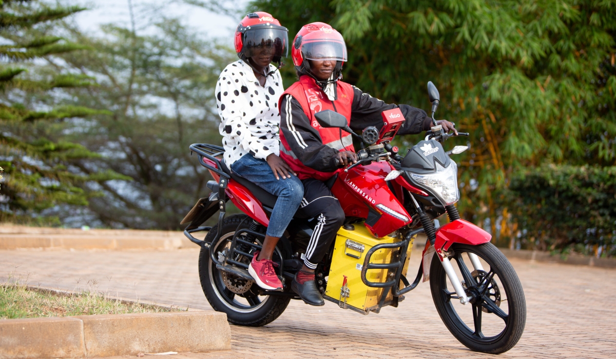 A female taxi moto driver Josie Nsanzingoma and her client on an  Ampersand e-motorbike in Kigali. File