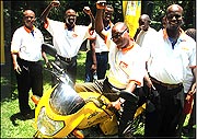 Vision Finance Company staff pose with a motorcycle they won from MTN.