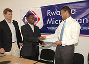 Tim Castrol, Director Micro Africa (L), Michael Kasibante, Managing Director Rwanda Micro Finance Stephane Le Boulder, Business Development Director Myc4 after signing a business deal (Photo/G. Barya).