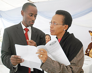 Directors General Emmanuel Muvunyi of SFAR (L) and Rose Mukankomeje of REMA peruse through a document at the function. (Photo J. Mbanda).