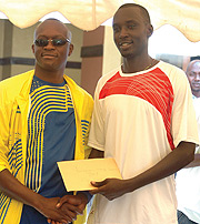 WINNERu2019S SMILE:  Jean Claude Gasigwa(R) gets his winneru2019s cash prize from Sports Minister Joseph Habineza .(Photo/ G. Barya)