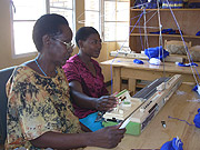 A senior woman teaching a young girl how to knit with a knitting machine.