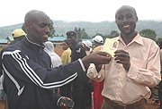 Executive Secretary, Emmanuel Rutabuuka (L) gives Projene Rutamu his medical insurance card yesterday. (Photo/ G. Barya)