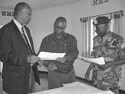 Capt. Musonera Director of Mutobo Demobilization Centre  presents lists of the ex combatants to RDFu2019s Maj.Gen. Paul Rwarakabije, (R).   Jean Sayinzoga looks on. 