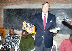 Ambassador Stuart Symington displays some of the books donated to the school yesterday. (Courtesy Photo)