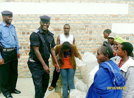 Ruhango Police Commander Supt. Fred Simugaya receives the collected polythene bags from residents. (Photo: D. Sabiiti)