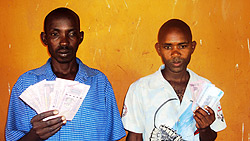 Samuel Hakizimana and James Gasirikare display the fake notes while under police custody. (Photo by S. Rwembeho)