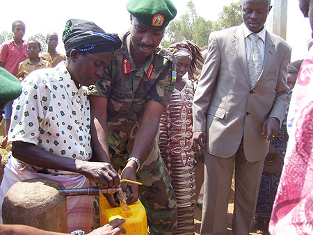 Lt.General Kayonga fills a container with clean tap water at Masoro Sector on Saturday. (Photo by A.Gahene)