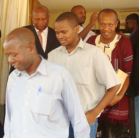 The two suspects, Simpson Mpirirwe (R u2013 in purple shirt), and Didas Ndamiye (C u2013 short sleeved shirt), being led by a Ugandan security official after being handed over, yesterday. Kabale Acting RDC, Vincent Bekunda (in neck-tie) looks on. (Photo B. Asiimw