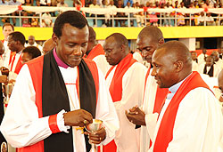 Louis Muvunyi the new consecrated Bishop of Kigali giving the Holy communion to fellow clergymen during the consecration (Photo T.Kisambira)