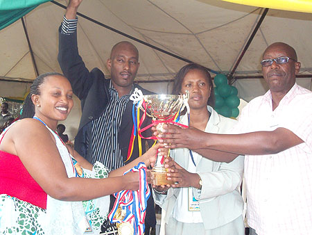 Jeanne D'arc Gakuba, the Kigali City Mayor in charge of Social Affairs (C), Rwandau2019s First Secretary to Uganda (in a black suit), Jacqueline Umulisa  and another guest pose with the trophy.