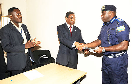 The Commissioner General of Police Emmanuel Gasana receives the software from Rodger Glokpor from the UN office for Disarmament Affairs.(Photo J Mbanda)