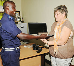 Gasabo District Police Commander Dismas Rutaganira (L) hands back the recoverred Money and Laptop to Walter Camilla at Remera Police Station. (Photo J Mbanda)