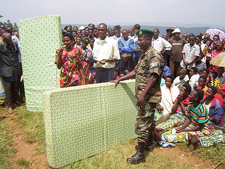 An RDF officer hands over mattresses to  residents during the Nyakatsi eradication drive in Giti Sector. Photo  A. Gahene